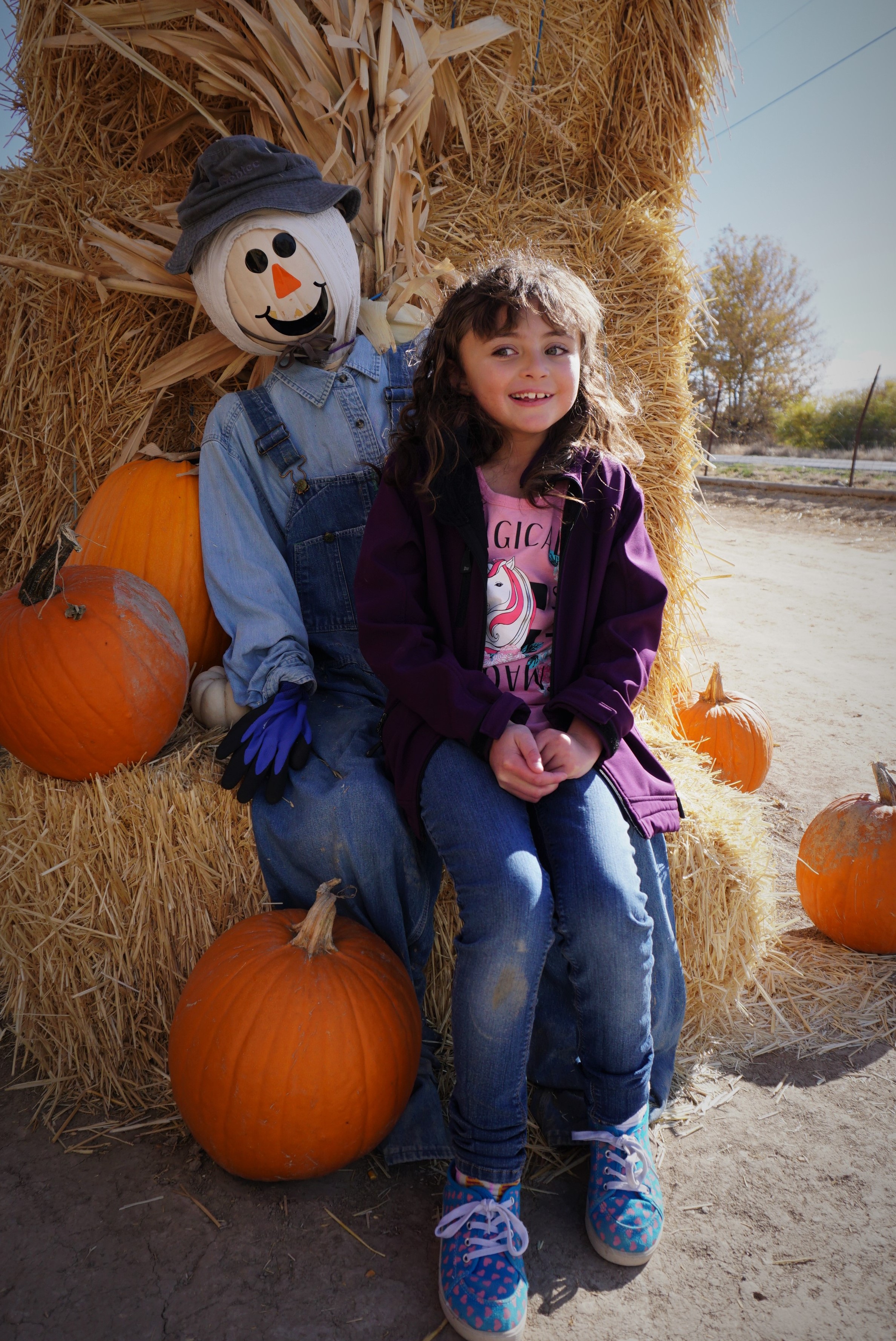 student poses with scarecrow